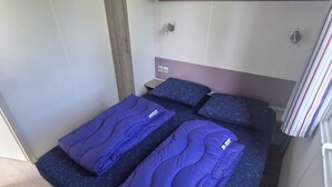 Un dormitorio pequeño con cama, espacio de almacenamiento integrado y ventana.
