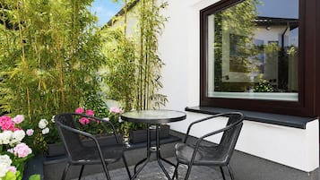 Une terrasse avec deux chaises et une table, entourée de plantes et de fleurs.