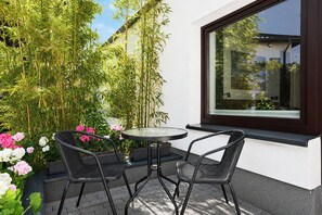 A patio with two chairs and a table, surrounded by plants and flowers.