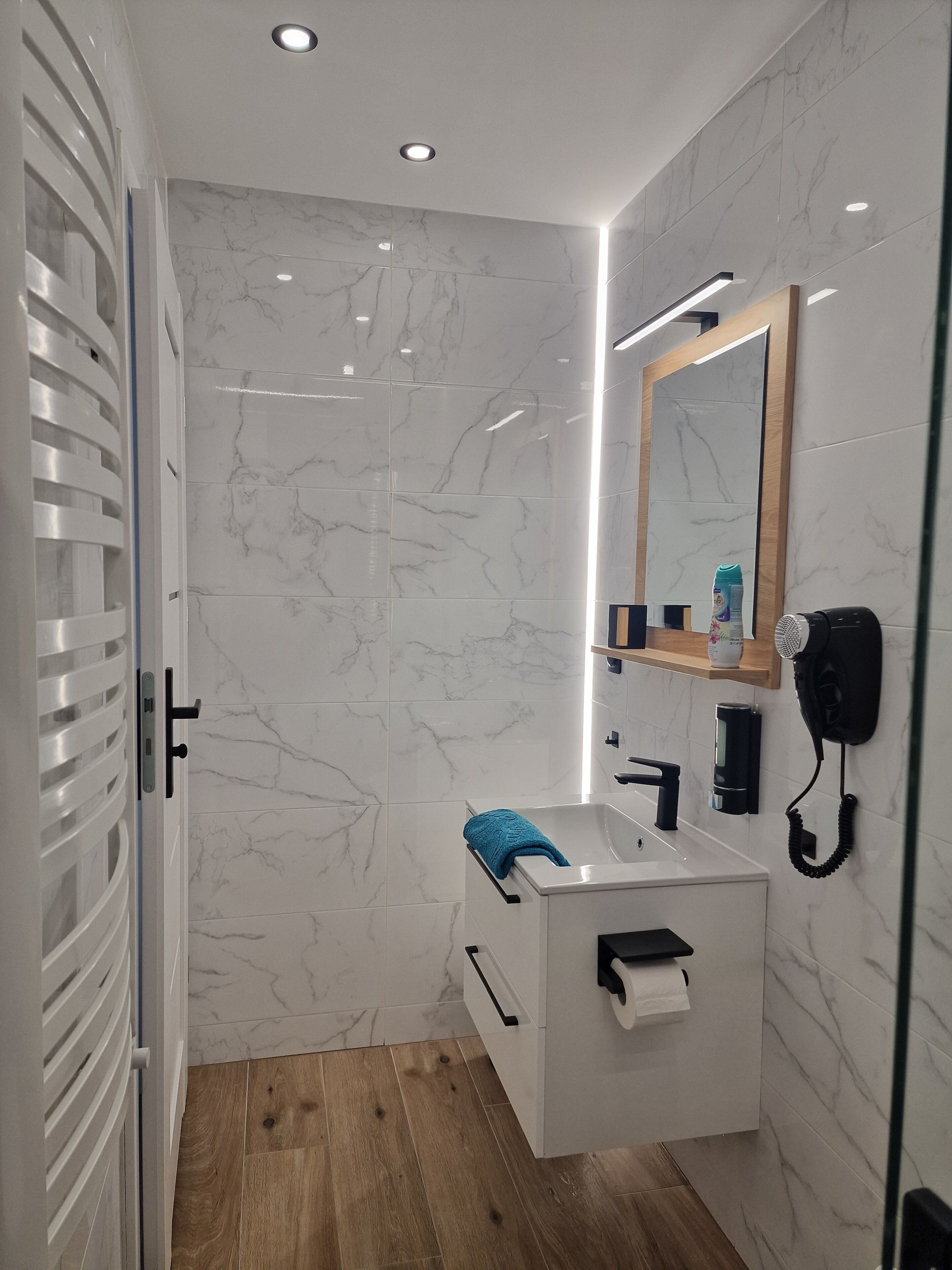 A modern bathroom with a white vanity, a mirror, a hairdryer, and a towel rack.