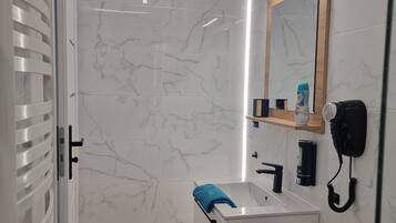 A modern bathroom with a white vanity, a mirror, a hairdryer, and a towel rack.