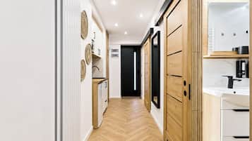 A hallway with wooden flooring, a white wall with decorative plates, and a black door at the end.