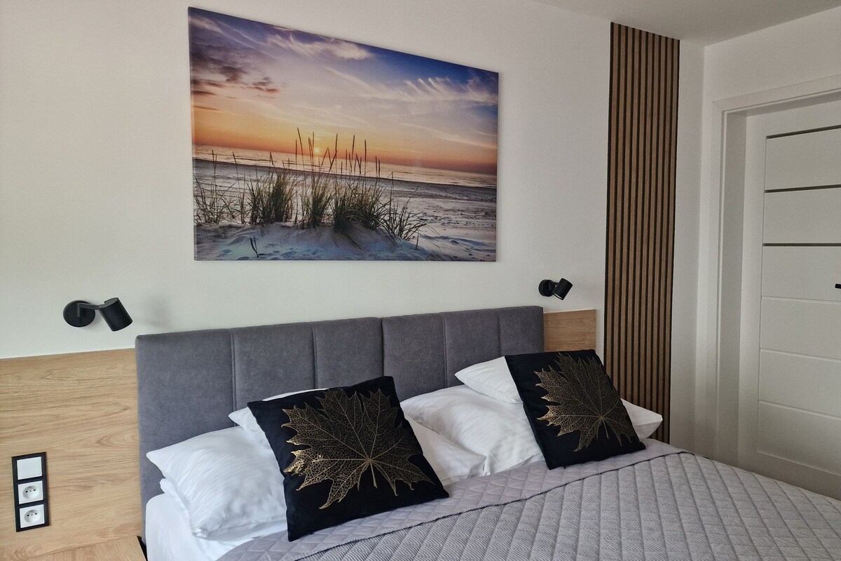 Ein Schlafzimmer mit einem Bett, einem Wandbild, einer Tür und einer Wandleuchte.