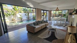 Amplia sala de estar con sofá, mesa de centro y vista a una piscina.