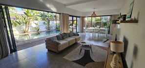 A spacious living area with a sofa, coffee table, and a view of a swimming pool. - Elegant villa with a pool • Beach: 2-minute walk • Golf: 3 min • Mont-Choisy (Mont-Choisy)
