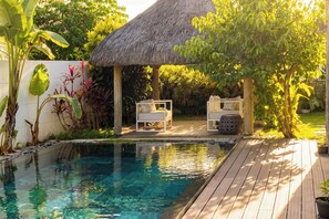 A pool area with a thatched roof, two white lounge chairs, and a wooden deck. - Elegant villa with a pool • Beach: 2-minute walk • Golf: 3 min • Mont-Choisy (Mont-Choisy)
