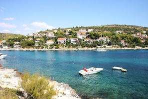 A coastal town with clear waters, boats, and houses on the hillside.