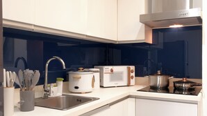 Ett modernt kök med vita skåp, en diskho i rostfritt stål, en brödrost, en vattenkokare och en spis.