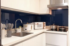 Een moderne keuken met witte kastjes, een roestvrijstalen spoelbak, een broodrooster, een waterkoker en een fornuis.