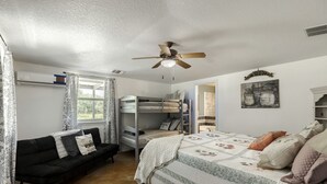 Ein Schlafzimmer mit Etagenbetten, einer Schlafcouch, einem Deckenventilator und einem Fenster mit Vorhängen.