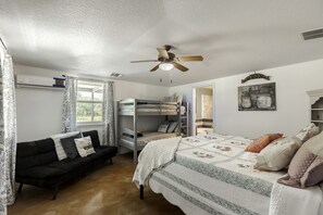 A bedroom with bunk beds, a sofa, a ceiling fan, and a window with curtains. - Rustic-Modern Ranch Retreat with Fire Pit & Nature Views in Mountain Home, Texas (Mountain Home)