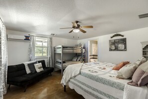 A bedroom with bunk beds, a sofa, a ceiling fan, and a window with curtains. - Rustic-Modern Ranch Retreat with Fire Pit & Nature Views in Mountain Home, Texas (Mountain Home)