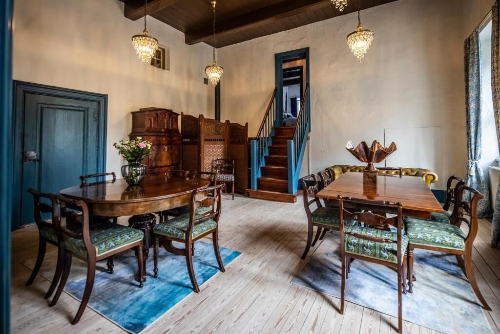 Un espace repas avec une table et des chaises en bois, un escalier et des lustres.