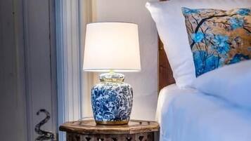 Ein Bett mit einem blumigen Kopfkissen, einer Nachttischlampe auf einem Holznachtisch und einem hölzernen Kopfteil.