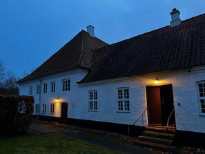 A white building with a steeply pitched roof and a dark entrance.