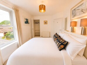A bedroom with a bed, a window, a door, and a hanging light fixture. - Rosemary House - Stylish home with garden in the heart of the South Downs (Petersfield)
