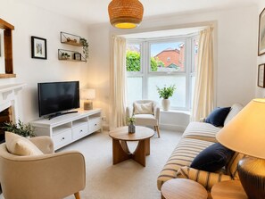 A living room with a TV, sofa, armchair, and a window with curtains. - Rosemary House - Stylish home with garden in the heart of the South Downs (Petersfield)