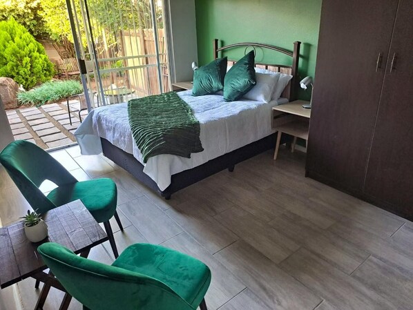 A bedroom with a bed, a desk, a chair, and a wardrobe.