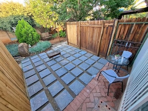 Une terrasse carrelée, une clôture en bois et du mobilier d’extérieur.