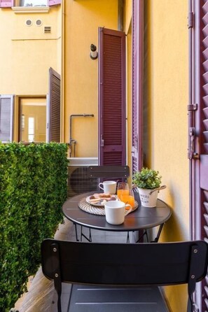 A small round table with a chair, a potted plant, a white mug, and a glass of orange juice. - Borromei 11  Eleganza in pieno centro (Milano)