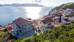 Une ville côtière avec des bâtiments, une vue dégagée sur la mer et un paysage vallonné en arrière-plan.