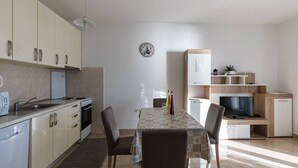Une cuisine moderne équipée d’une table à manger, de chaises, d’un réfrigérateur et d’un téléviseur.