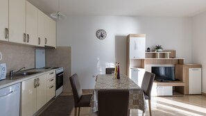 Eine moderne Küche mit Esstisch, Stühlen, einem Kühlschrank und einem Fernseher.