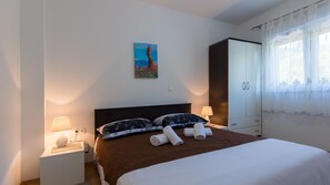Ein Hotelzimmer mit Bett, zwei Nachttischlampen, einem Nachttisch, einem Kleiderschrank und einem Bild an der Wand.