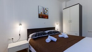 A hotel room with a bed, a nightstand, a wardrobe, and a painting on the wall. - Apartman Arapovic 4 by Villas Guide (Klek)