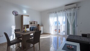 A modern living room with a dining area, a sofa, and a view of the sea through large windows. - Apartman Arapovic 4 by Villas Guide (Klek)