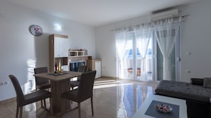Ein modernes Wohnzimmer mit Essbereich, einer Couch und Meerblick durch große Fenster.