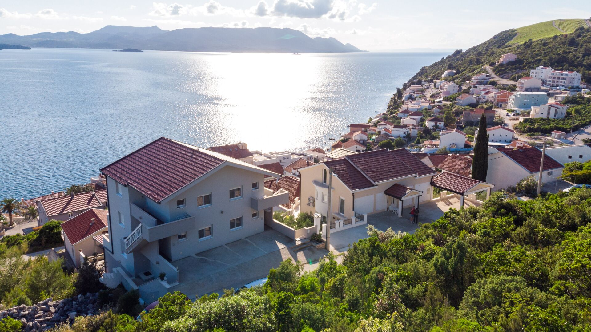 Un pueblo costero con edificios, una vista despejada del mar y un paisaje montañoso al fondo.