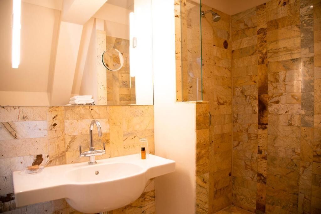 Un baño con lavabo, espejo y ducha.