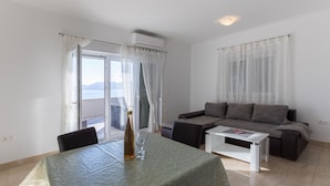 A living room with a sofa, a coffee table, and a dining table with a bottle and glass. - Apartman Arapovic 2 by Villas Guide (Klek)