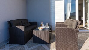 Eine Terrasse mit Korbmöbeln, einem Tisch und einer Fruchtschale sowie einer Orangensaftflasche.