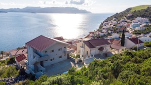 A coastal town with buildings, a clear view of the sea, and a hilly landscape in the background. - Apartman Arapovic 2 by Villas Guide (Klek)