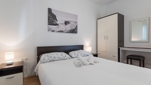A bedroom with a bed, a desk, a chair, a wardrobe, and a painting on the wall. - Apartman Arapovic 2 by Villas Guide (Klek)