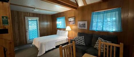 Una habitación con cama, sofá, mesa y ventana con cortinas.