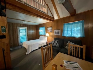 Een kamer met een bed, een bank, een tafel en een raam met gordijnen.