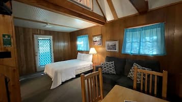 Ein Zimmer mit einem Bett, einem Sofa, einem Tisch und einem fenster mit Vorhängen.