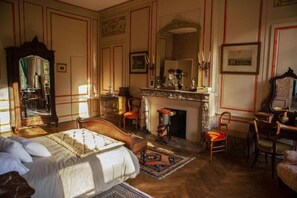 Un dormitorio con cama, chimenea, espejo y escritorio.