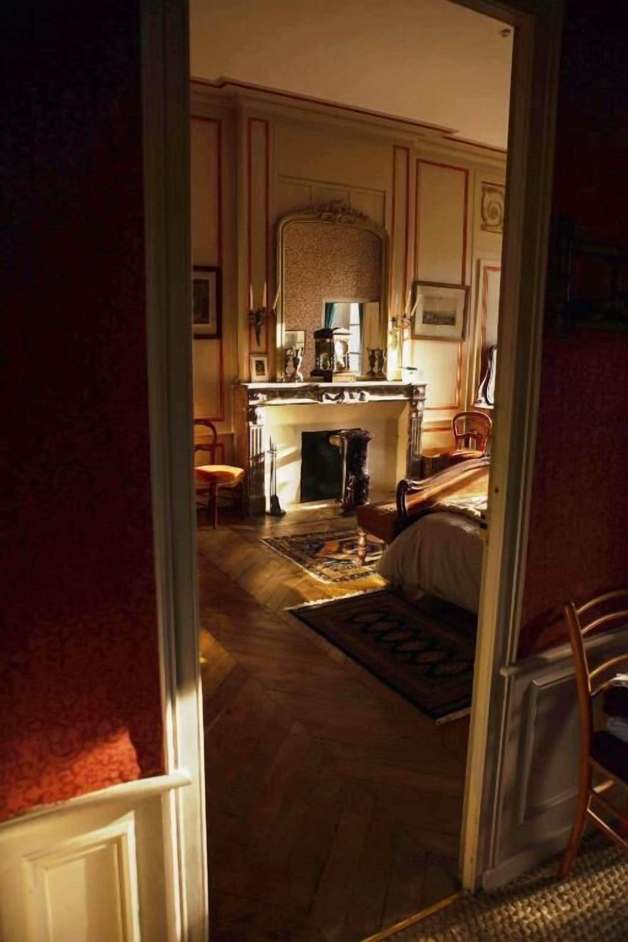 An interior view of a room with a fireplace, a mirror, and a rug on the floor.