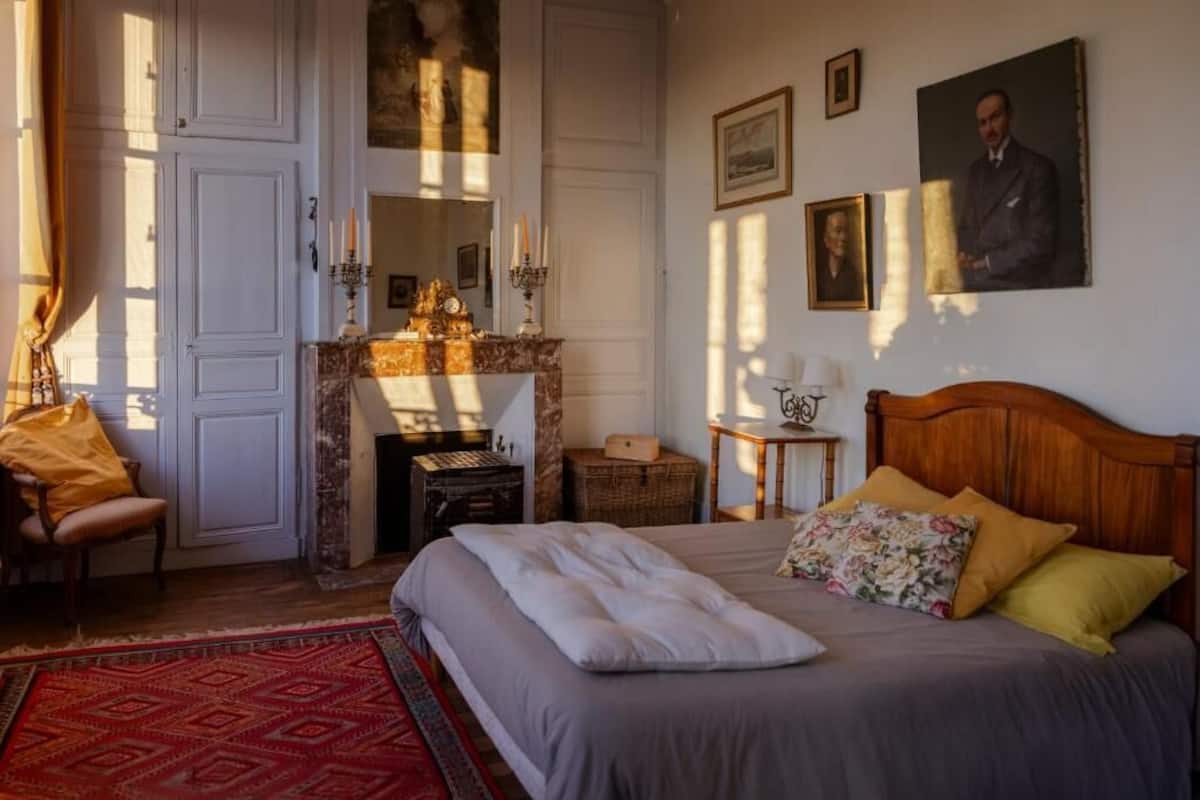 Un dormitorio con una cama, una chimenea, una silla y una alfombra.