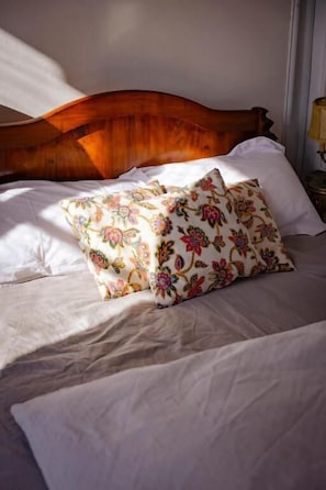 Un llit amb roba de llenc i una almoinada amb estampat floral.
