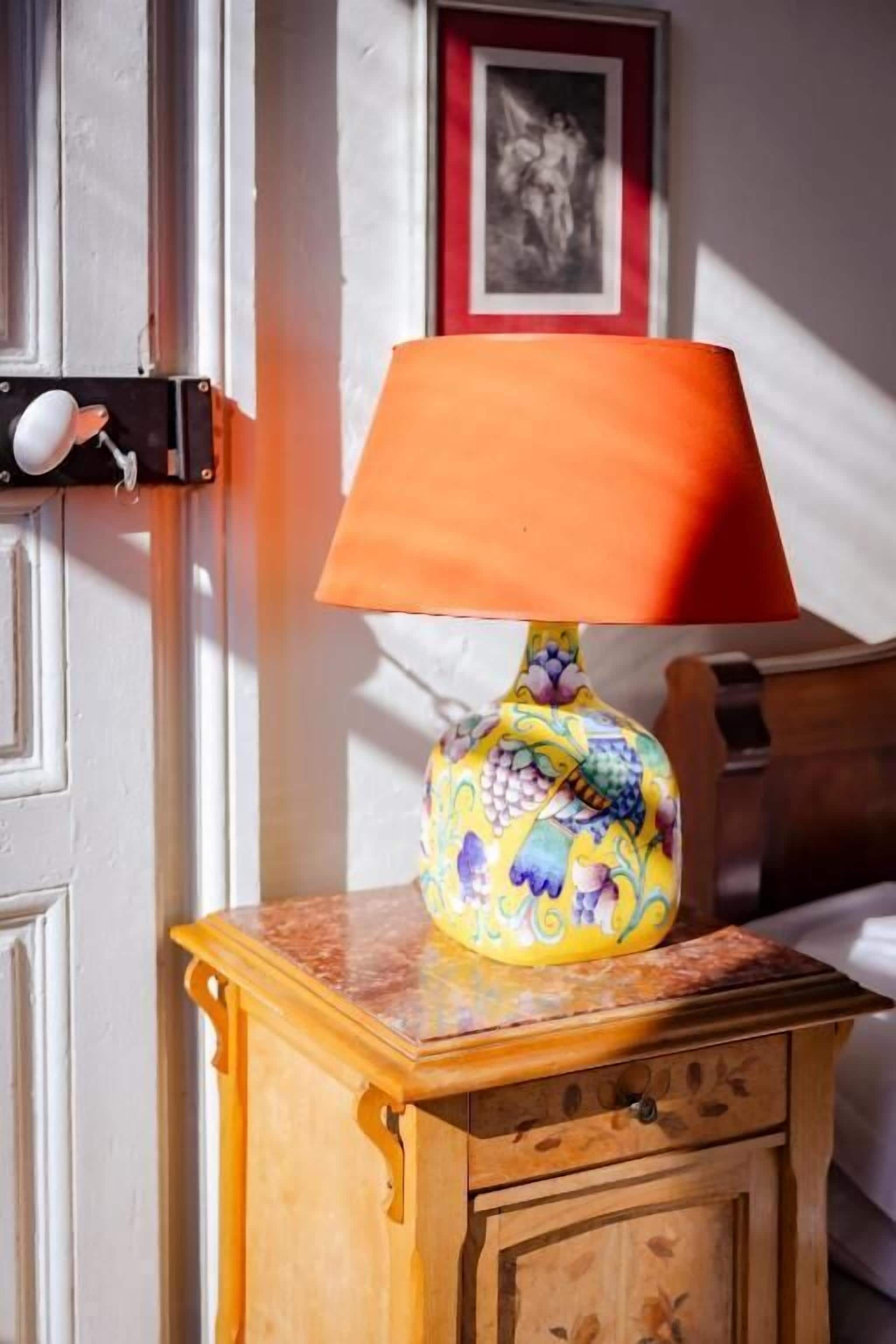 A lamp with a colorful base on a wooden nightstand.