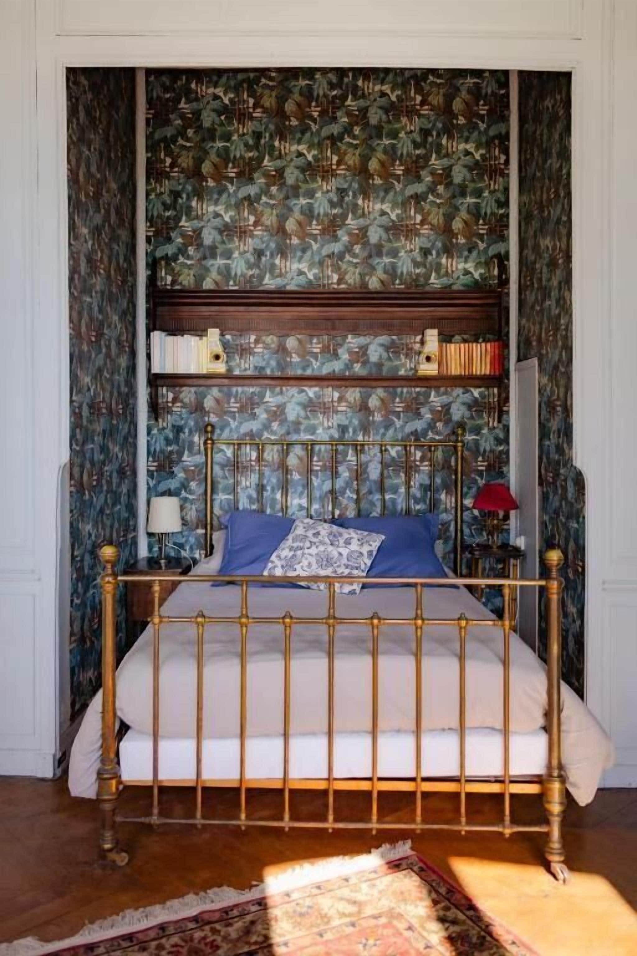Un dormitorio con cama, estantería y papel tapiz estampado.