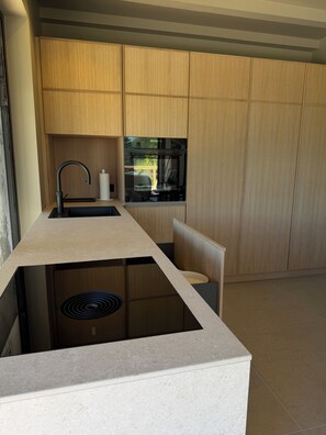 A modern kitchen with built-in appliances, a sink, and wooden cabinets.