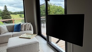 A modern living room with a sofa, ottoman, and a flat-screen TV.