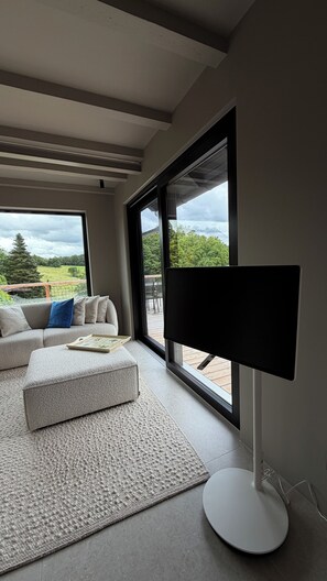 A modern living room with a sofa, ottoman, and a flat-screen TV.
