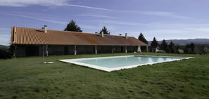 Una casa moderna con piscina, immersa in un prato verde e alberi.
